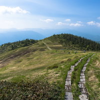 会津駒ヶ岳の稜線を歩む木道と青空の高原風景の写真