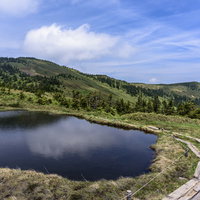 会津駒ヶ岳の高層湿原を歩む木道と水鏡に映る空と雲の写真