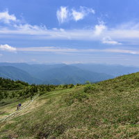 会津駒ヶ岳の稜線を行く登山者たちと高原の木道の写真
