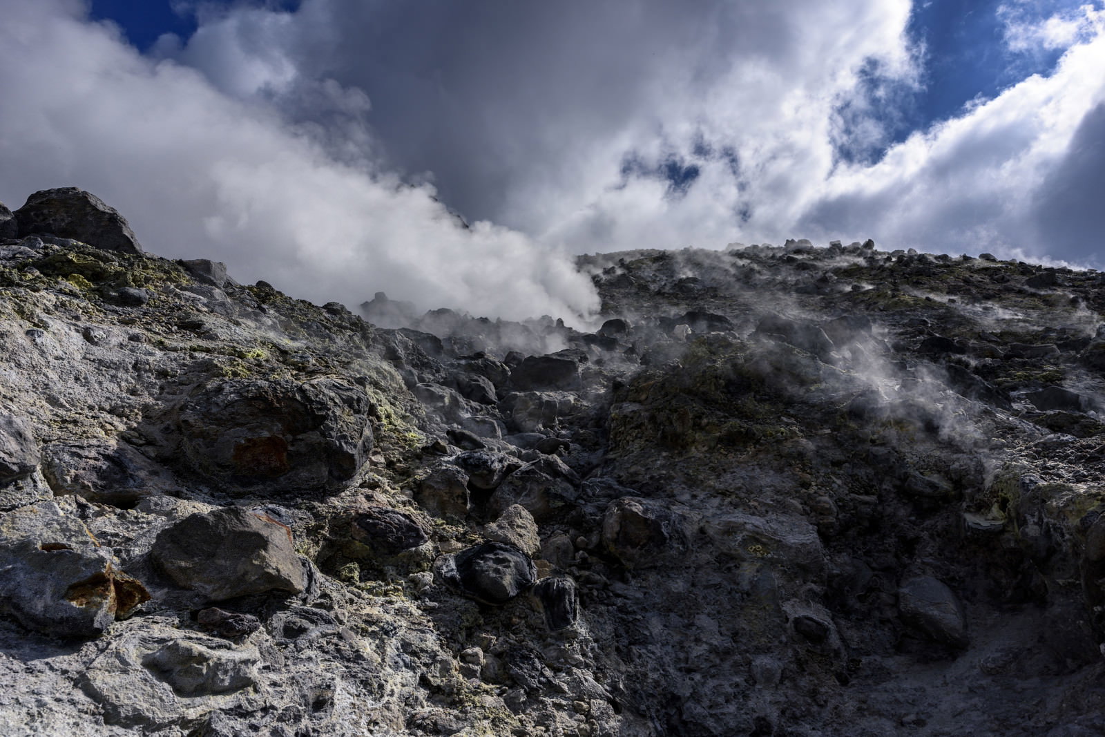 那須茶臼岳の火山岩から白い煙が立ち上る様子を青空をバックに撮影