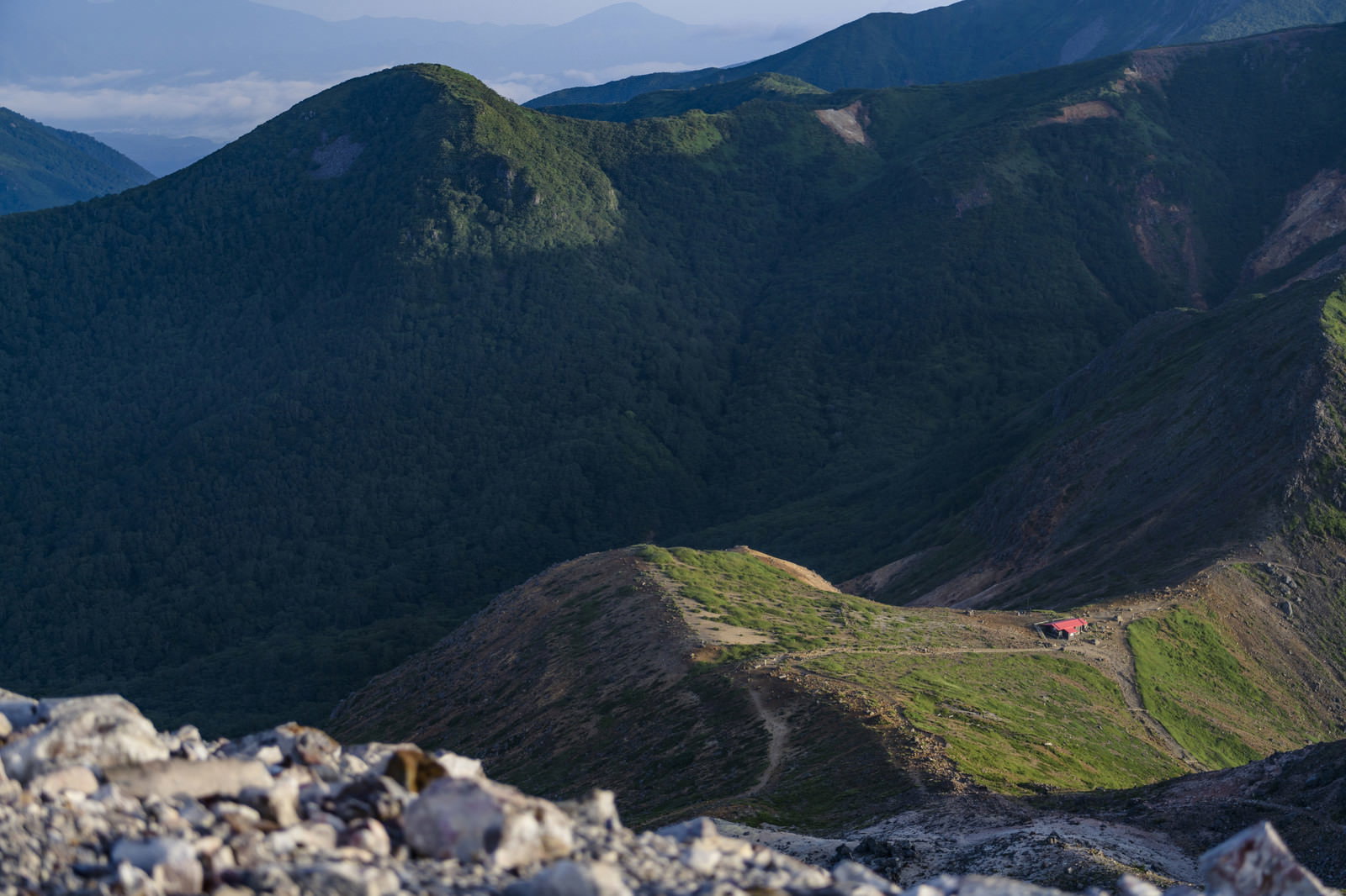 那須岳の山中に建つ避難小屋と連なる山稜の風景
