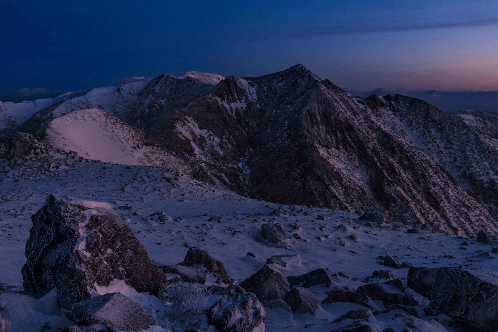 雪に覆われた那須朝日岳に夜明けの光が当たる冬の山岳風景
