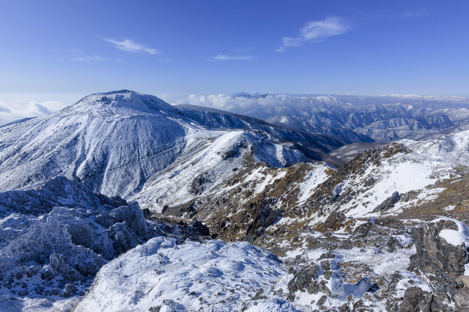 雪に覆われた那須岳の山稜と青空、遠景に連なる山々