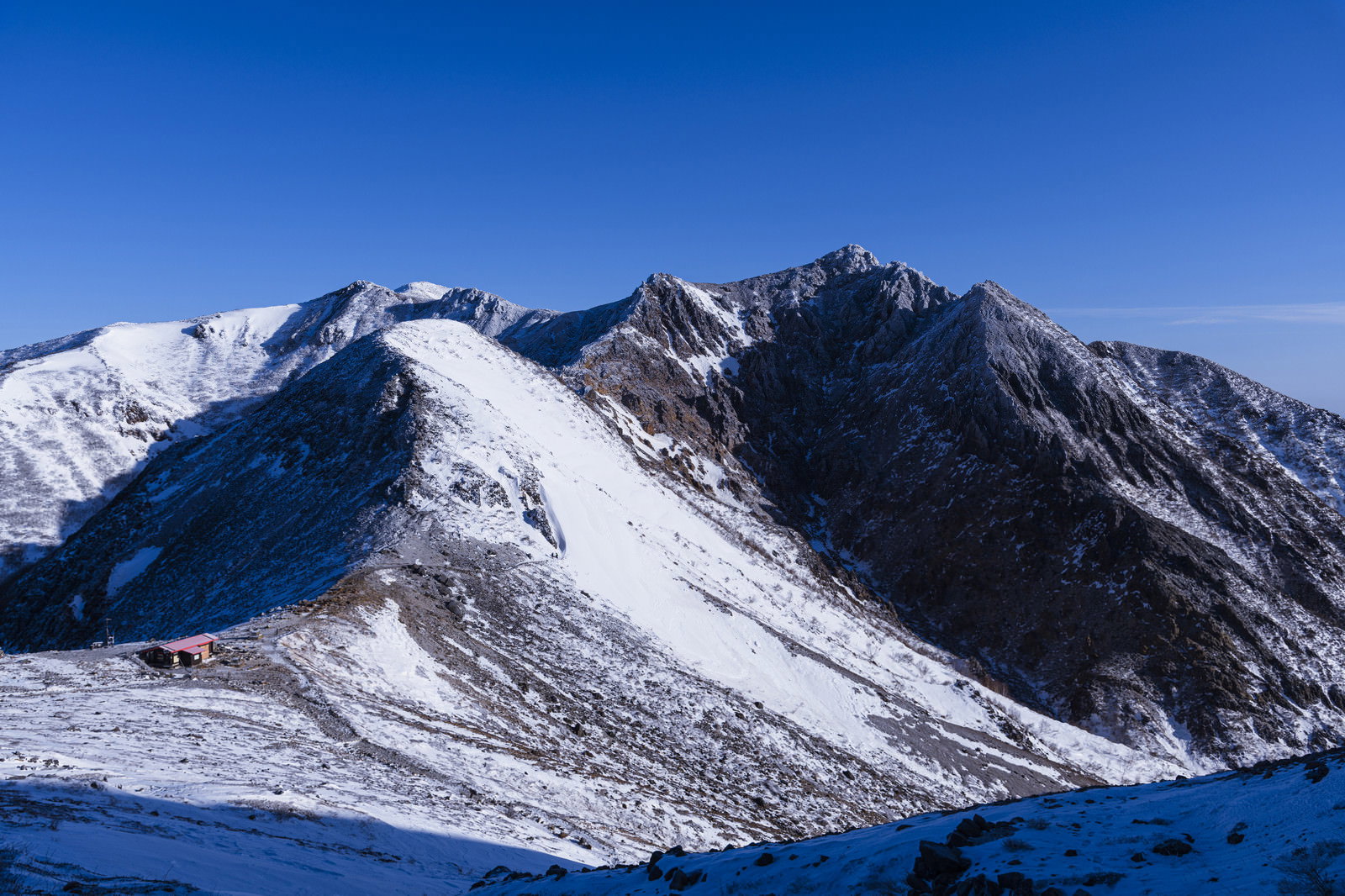 青空の下に雪化粧した那須岳の山稜が連なる冬の風景