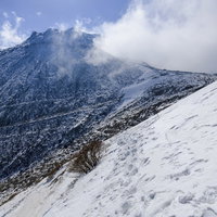 剣ヶ峰中腹から眺める雪化粧の那須茶臼岳と冬の山岳風景の写真