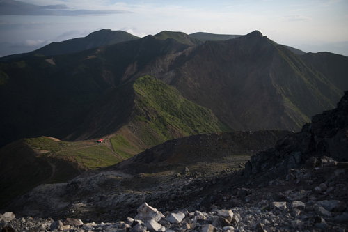 午前の柔らかい光が差す那須岳避難小屋と成層火山の山容