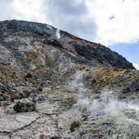 山頂へと続く噴気沸き立つがけ、那須岳の成層火山の写真
