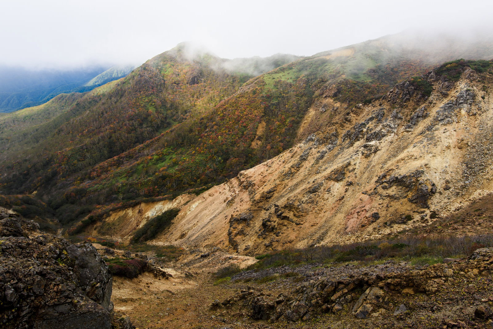 那須岳の崩落した岩肌の斜面と背景に広がる紅葉した山々