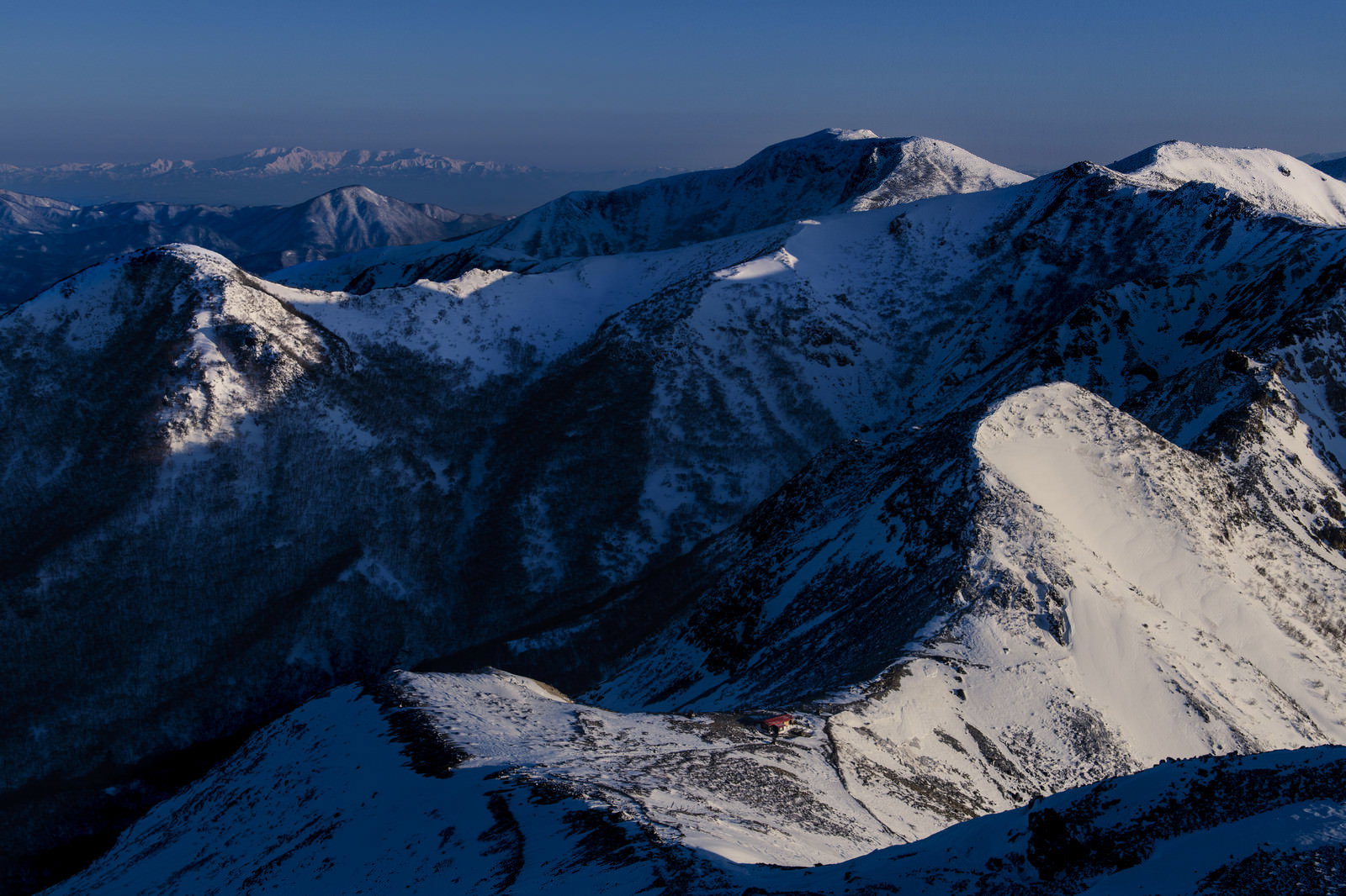 青い空の下、雪に覆われた那須連山の峰々が連なる朝の山岳風景