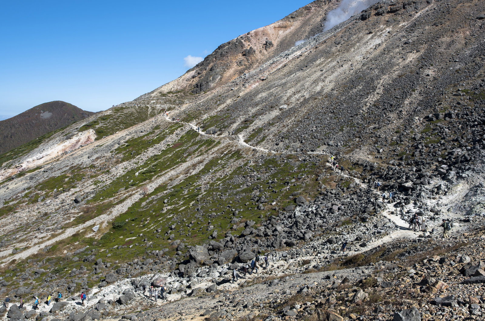 火山地帯の斜面を登る登山者たちと那須茶臼岳の荒野