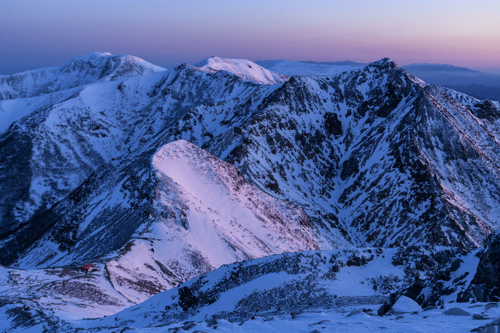 夜明け前の薄明に染まる雪化粧した那須岳の山並み