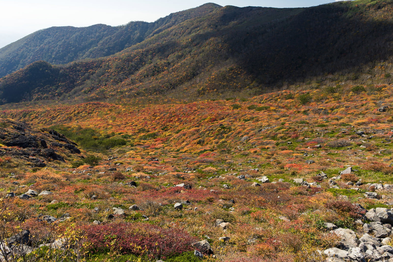紅葉で赤やオレンジに染まった那須茶臼岳の中腹と背景の山々
