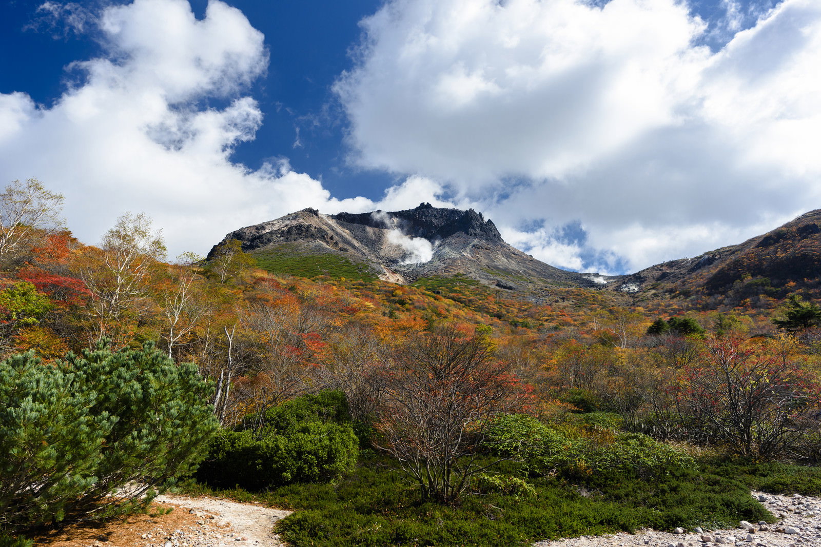 青空の下、紅葉に染まった姥ヶ平と背後に聳える那須岳の山岳風景