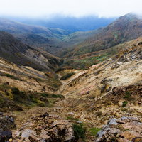 那須岳の裂けた谷間と成層火山の中腹に広がる紅葉の写真
