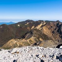 那須朝日岳へと至る稜線で見る青空と岩場の登山道（那須岳）の写真