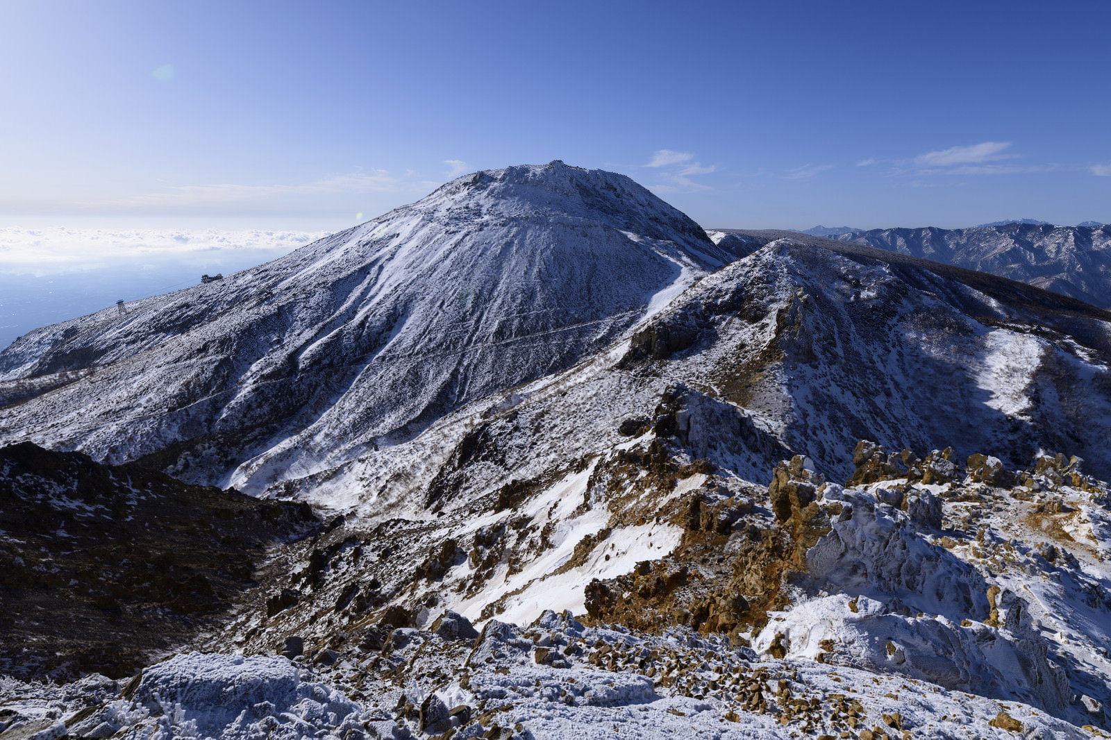 雪に覆われた那須茶臼岳の山頂付近、青空と山々の風景