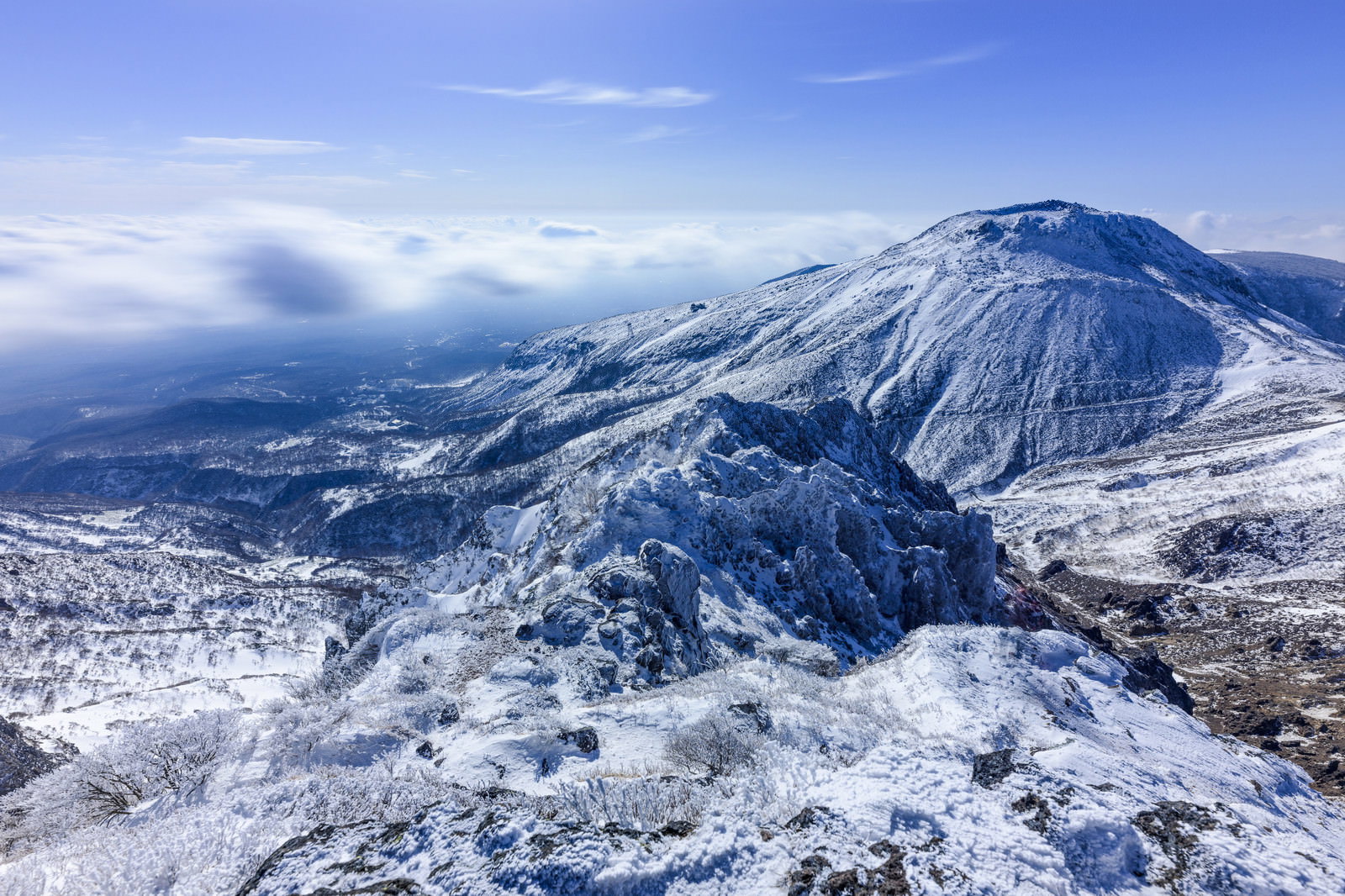 雪に覆われた那須茶臼岳の山頂と青空に流れる白い雲