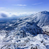 雪に覆われた那須茶臼岳と流れゆく雲の写真