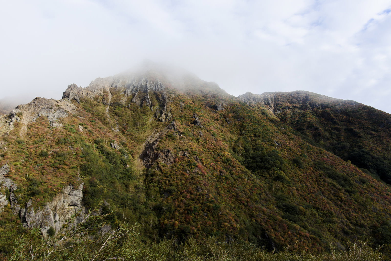 雲に覆われた那須朝日岳の紅葉した山肌