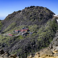 ザレ場に建つミニチュアのような鳥海山の山小屋の写真