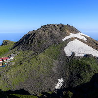 快晴の鳥海山山頂の岩稜地帯を歩む登山者たちの写真