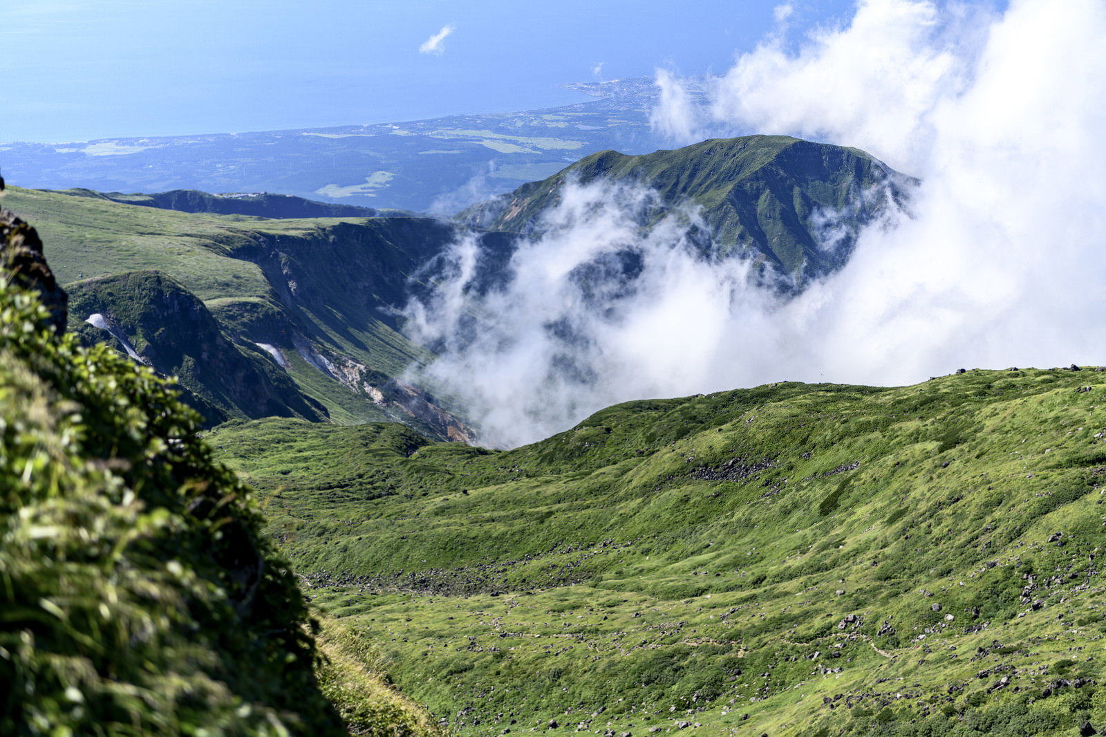 緑の山肌から白い雲が湧き上がる鳥海山山頂の風景