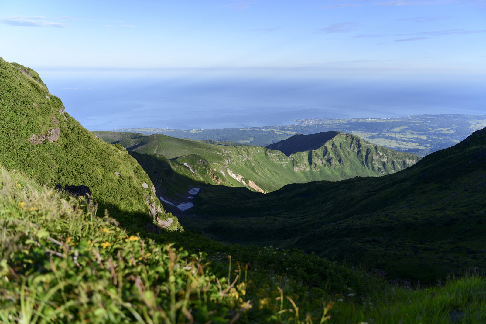 鳥海山外輪から見下ろす緑の山肌と遠方に広がる日本海の景色