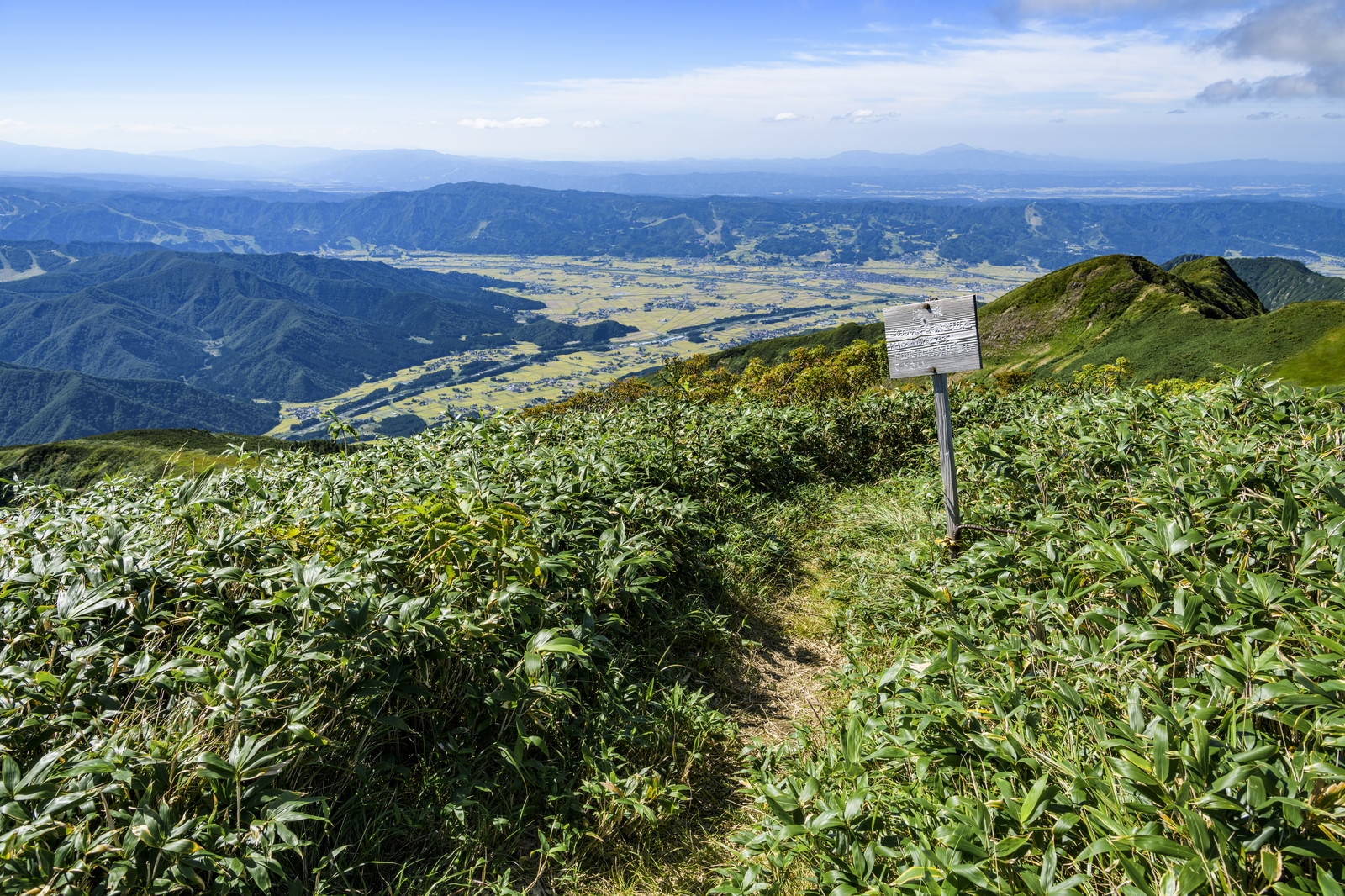 割引山から魚沼方面を見下ろす景色と登山道の看板