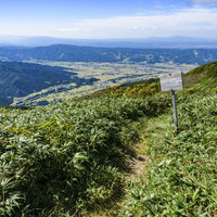 割引山から見える魚沼方面の景色と登山道の看板（巻機山）の写真