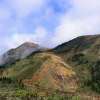 雲がかかる割引山と巻機山の稜線 日本百名山の山並みの写真