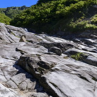 悠久の水の流れで削られた滑沢の岩（巻機山のヌクビ沢）の写真