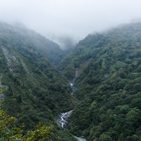 雲に包まれた巻機山ヌクビ沢の山肌と沢筋の景観の写真