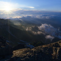 白馬岳山頂から見る朝日と雲海に浮かぶ山々の稜線の写真