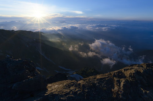 白馬岳山頂から見る朝日と雲海に浮かぶ山々の稜線