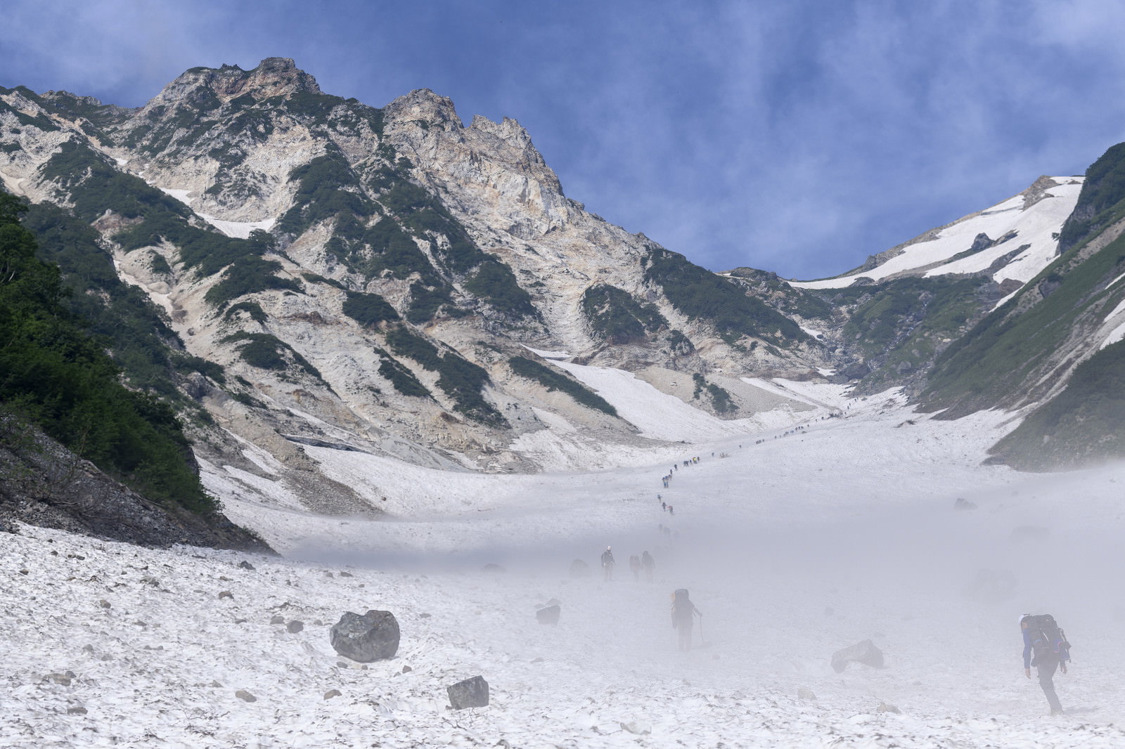 白馬岳の雪渓を進む登山者たちと雪に覆われた山々の風景