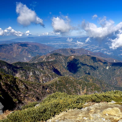 甲斐駒ヶ岳山頂から見る紅葉に染まる南アルプスの山々の写真