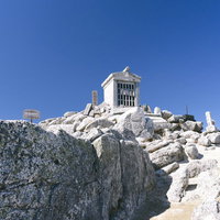 甲斐駒ヶ岳山頂の白い社と花崗岩の岩場の壮大な景観の写真