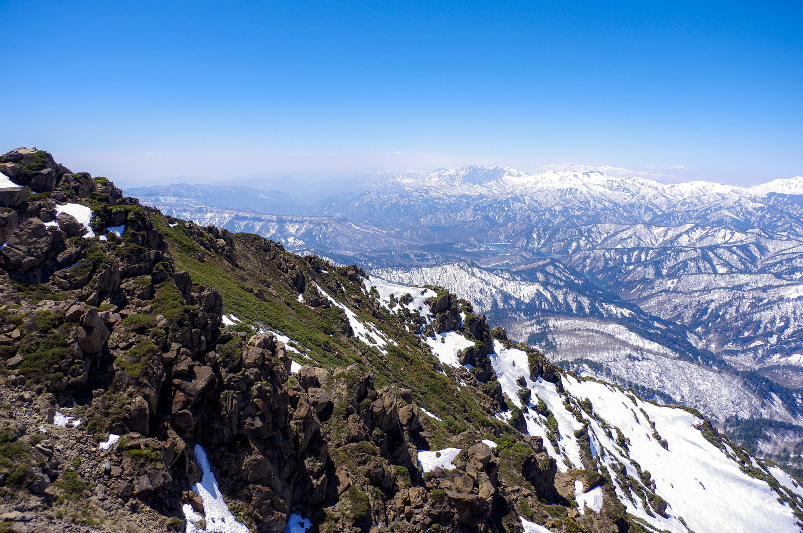 青空の下、雪解けが始まった至仏山と上越の山並みを捉えた山岳風景