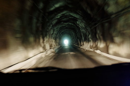 両神山への素掘りトンネルを走る車と出口の光