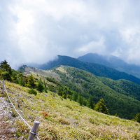 雲に覆われる大菩薩嶺の稜線と登山道を歩く登山者の写真