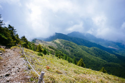 雲に覆われる大菩薩嶺の稜線と登山道を歩く登山者