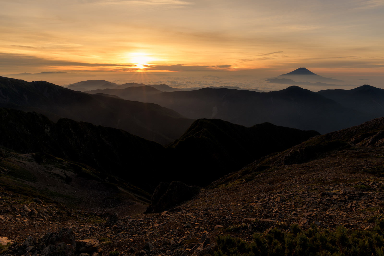 赤石岳山頂から見た朝焼けの空と富士山のシルエット