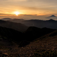 赤石岳山頂から朝焼けに染まるご来光と富士山（南アルプス）の写真