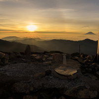 朝日に照らされハロが見える赤石岳山頂碑（南アルプス）の写真