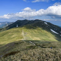 晴れ間に照らされる仙ノ倉山の稜線と登山道の写真