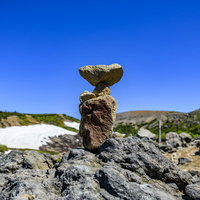 快晴の空に映える積み上がるケルン（積み石）の道標の写真