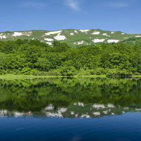 湖面に反射する焼石岳と奥羽山脈の雄大な山岳風景の写真