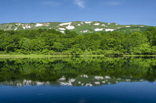 湖面に反射する焼石岳と奥羽山脈の雄大な山岳風景