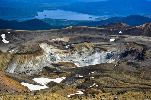 雌阿寒岳の火口から立ち上る噴煙と阿寒湖周辺を一望する景色