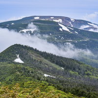 雲を纏う蔵王連峰の登山道から眺める重なり合う山々の景色の写真
